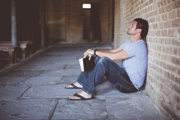 Man holding book frustrated against wall.