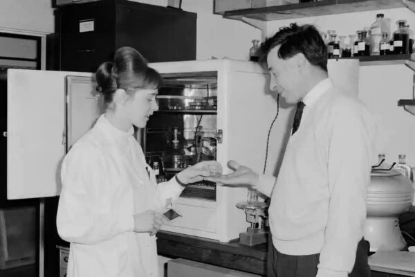 Old black and white photo of man and woman in lab.
